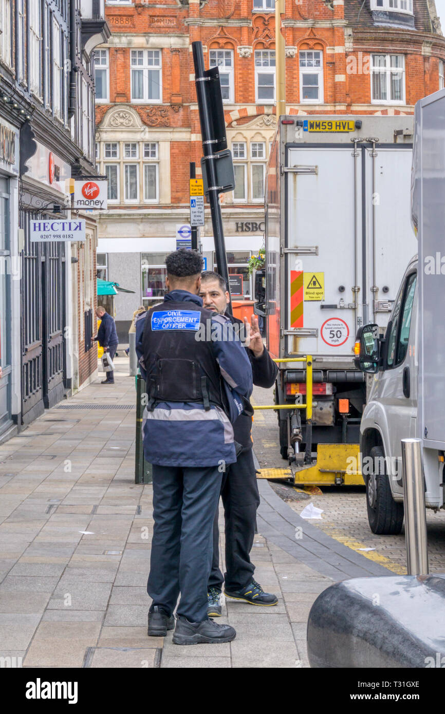 Lieferung Fahrer diskutieren Parkbeschränkungen mit einem zivilen Vollstreckungsbeamten. Stockfoto