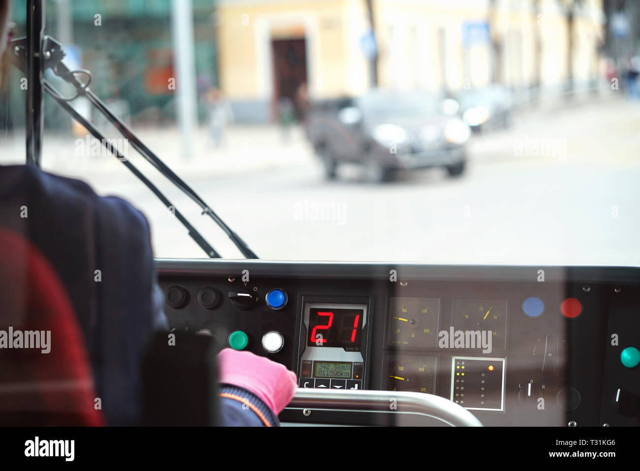Straßenbahnfahrer, der den Zug steuert. Person, die mit einem Straßenwagen auf der Straße fährt. Blick auf das Armaturenbrett im Cockpit und Verkehr mit Autos im Fenster. Stockfoto