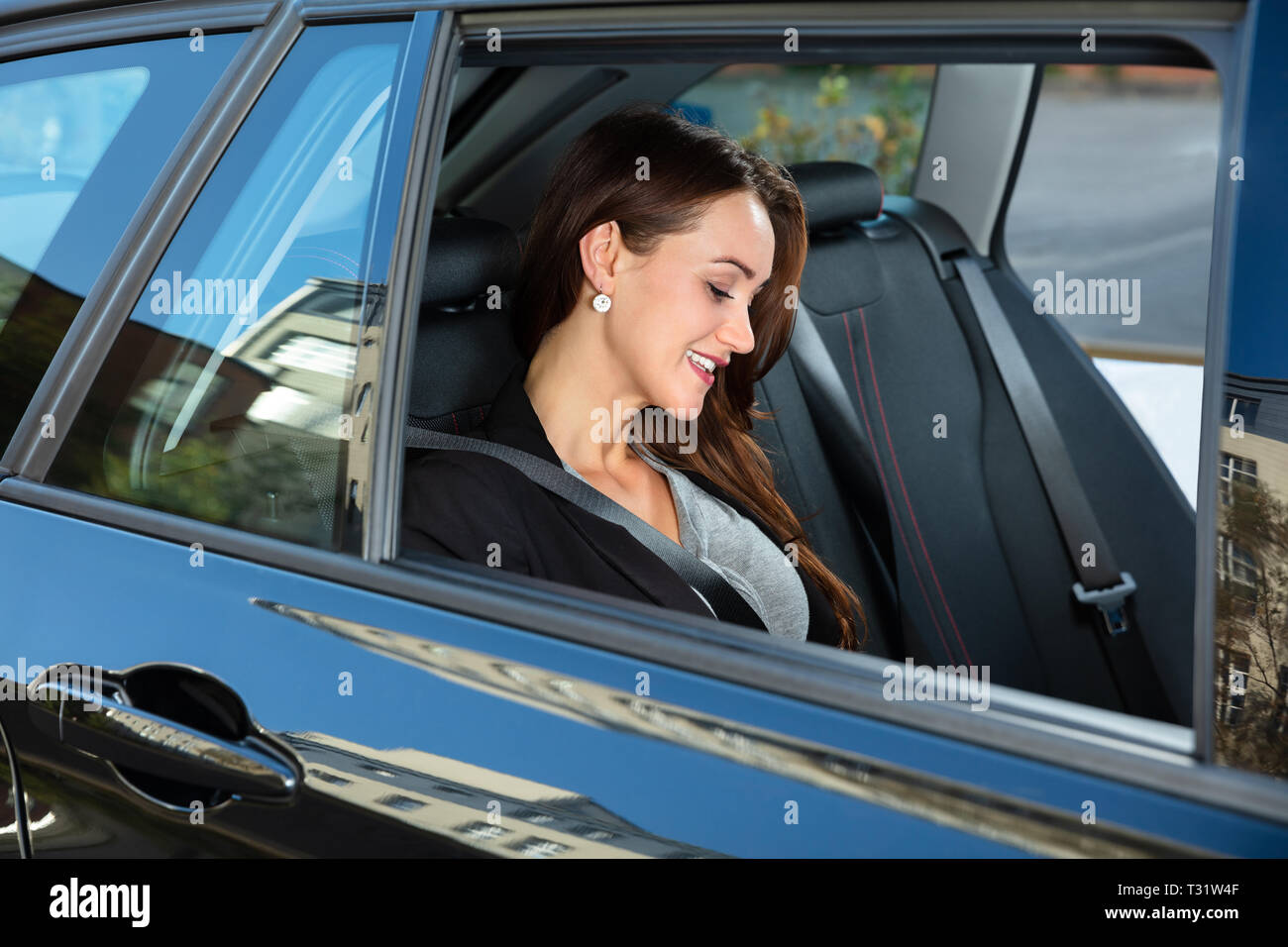 Seitenansicht des lächelnden Jungen Geschäftsfrau, Sitzen im Auto. Stockfoto