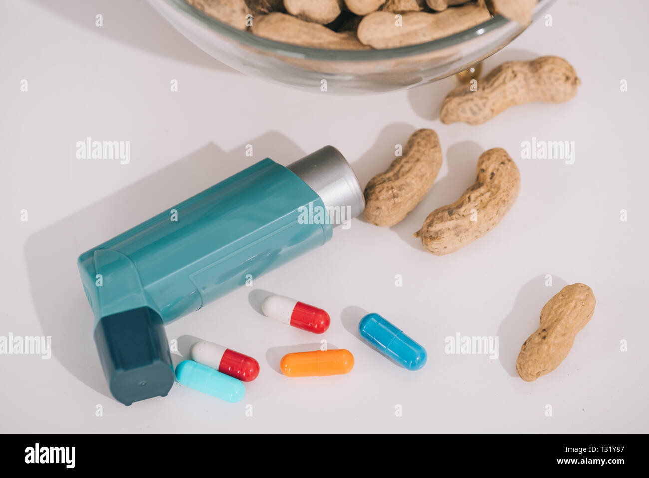 Leckere Erdnüsse in der Nähe von Blue Inhalator und Pillen auf Grau Stockfoto