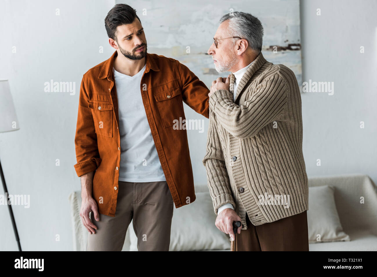 Schöne bärtige Sohn Hand auf der Schulter der traurige senior Vater in Gläser Stockfoto