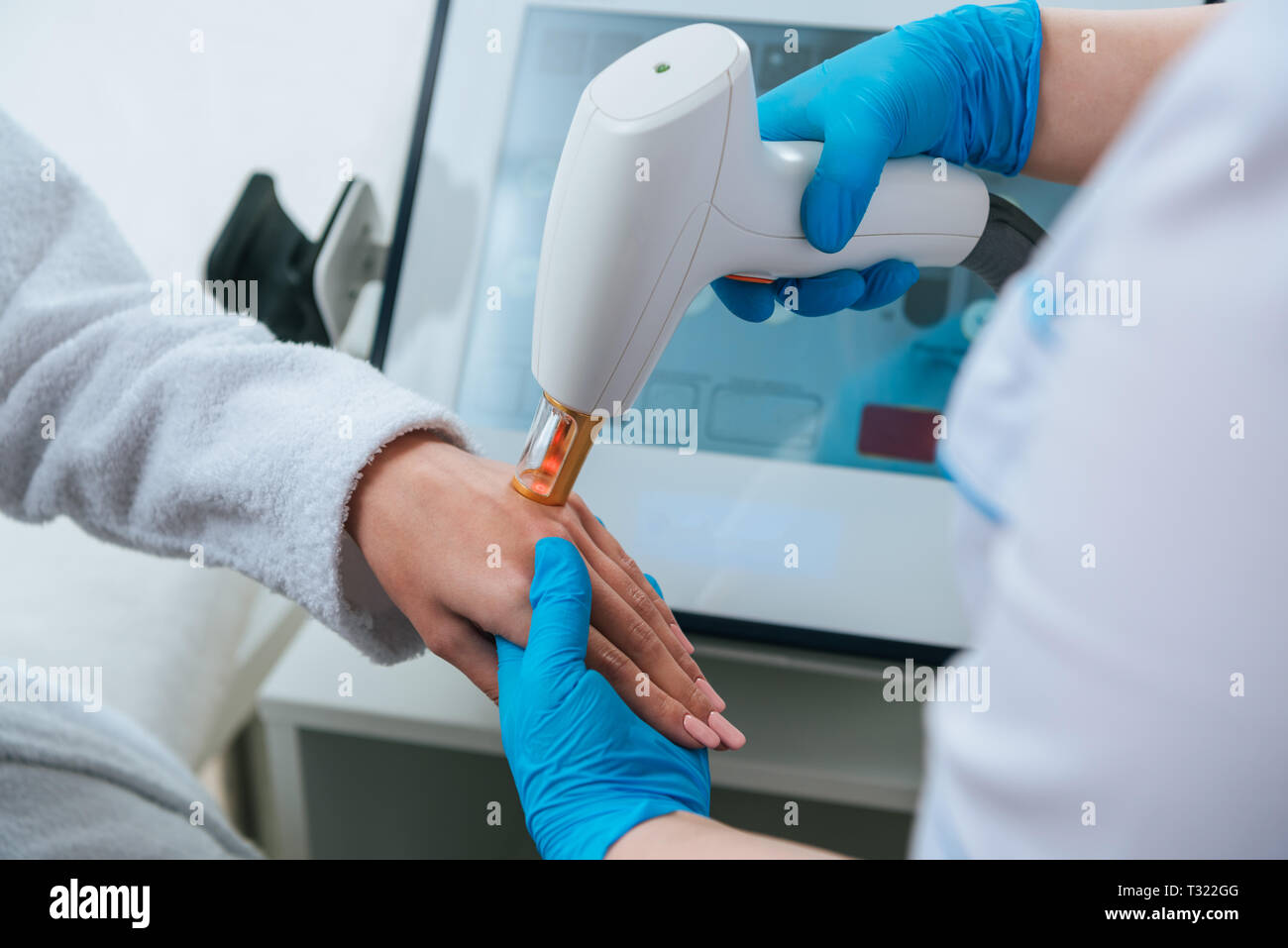 7/8-Ansicht der Kosmetologin tun Laser Haarentfernung Verfahren an Hand Stockfoto