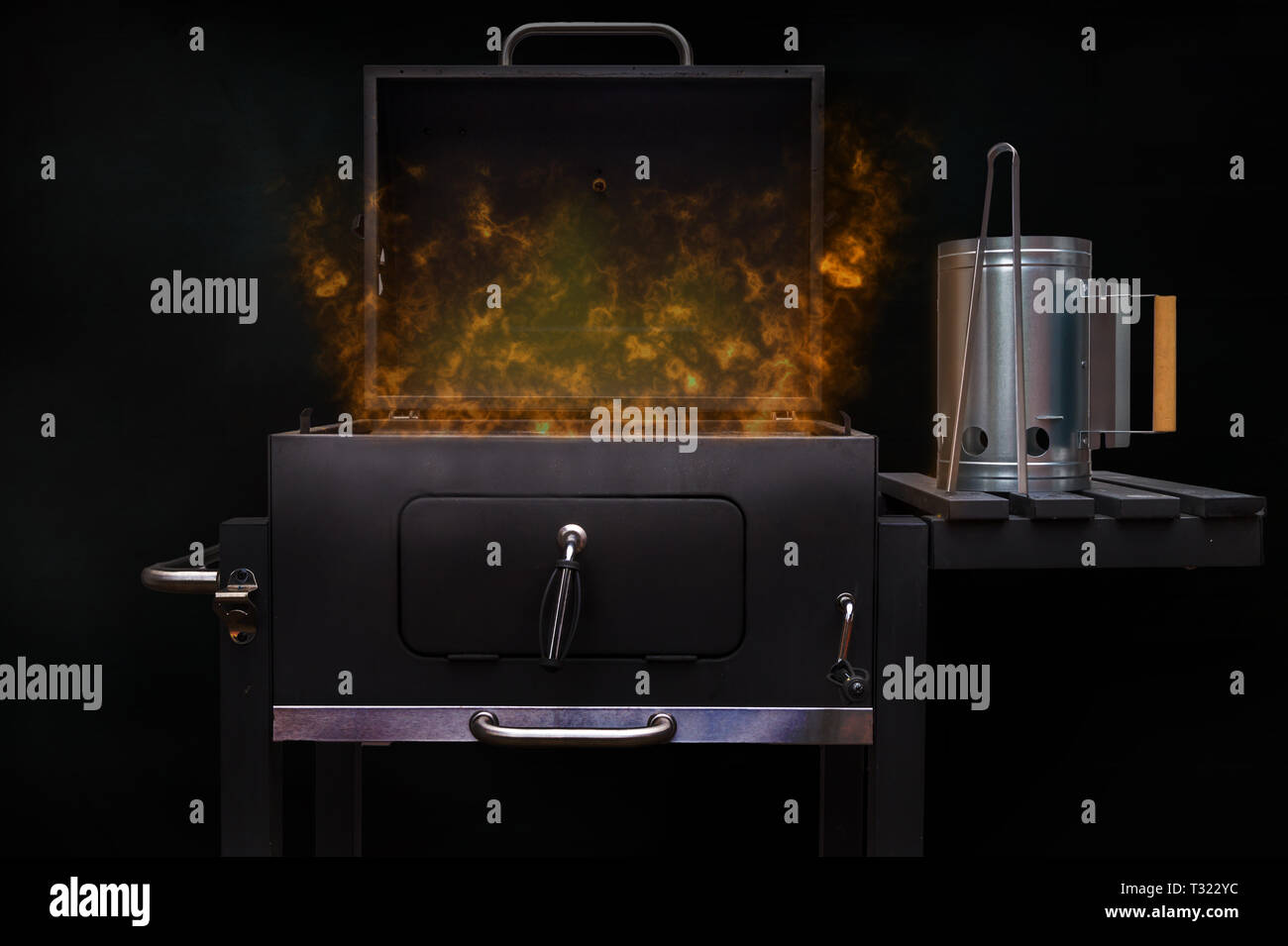 Ein flammendes Holzkohlegrill vor einem schwarzen Hintergrund. Konzept für bbq Partys. Stockfoto
