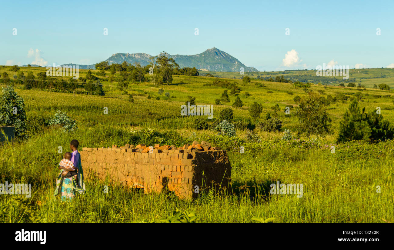 Malawische Frau und Kind vorbei ein Brennofen für verbrannte Hand Steine in eine malawische Dorf Stockfoto