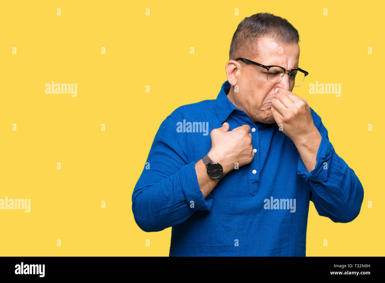 Mittleres Alter arabischer Mann Brille über isolierte Hintergrund riechen etwas stinkig und ekelhaft, unerträglichen Geruch, Atem wird mit den Fingern Stockfoto