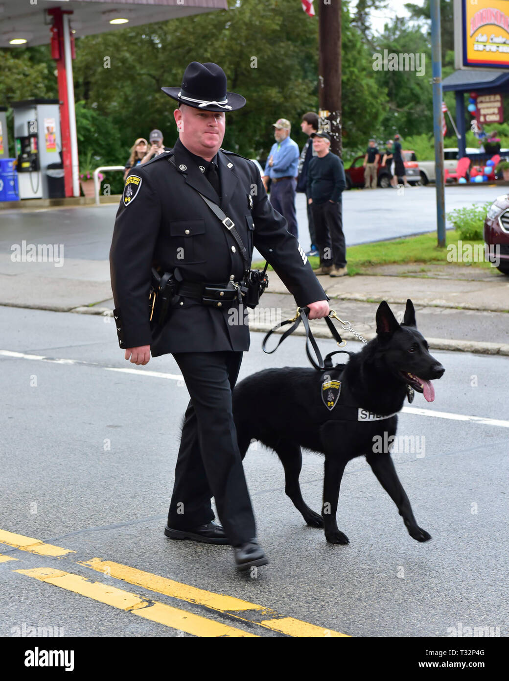 Ein Polizeioffizier in der 4. Juli Parade marschiert mit seinem K-9 Polizei Hund in Spekulant, NY, USA Stockfoto