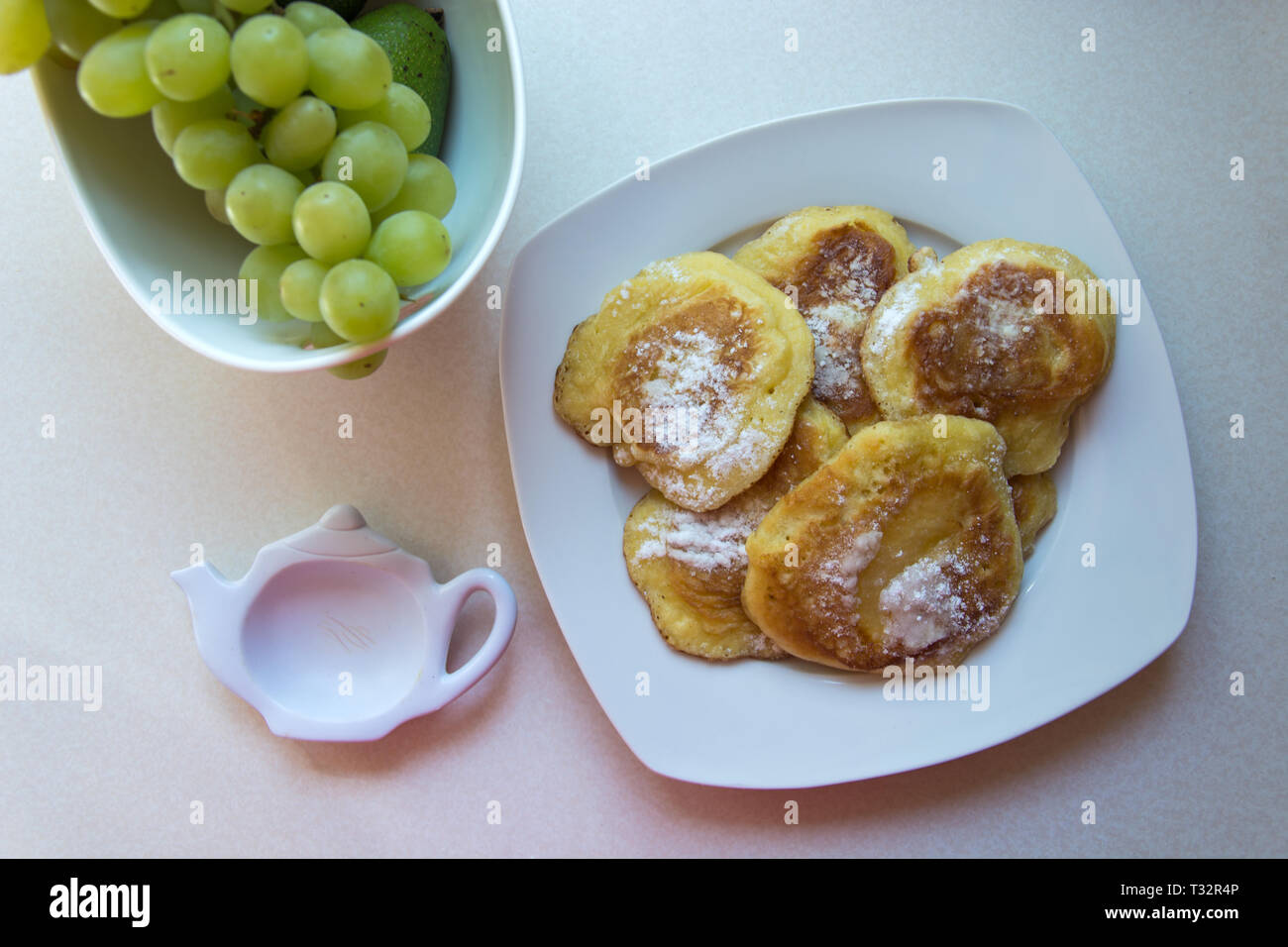 Traditionelle polnische Pfannkuchen auf einen Teller und grüne Trauben - Süße Pfannkuchen mit Puderzucker bestreut Stockfoto