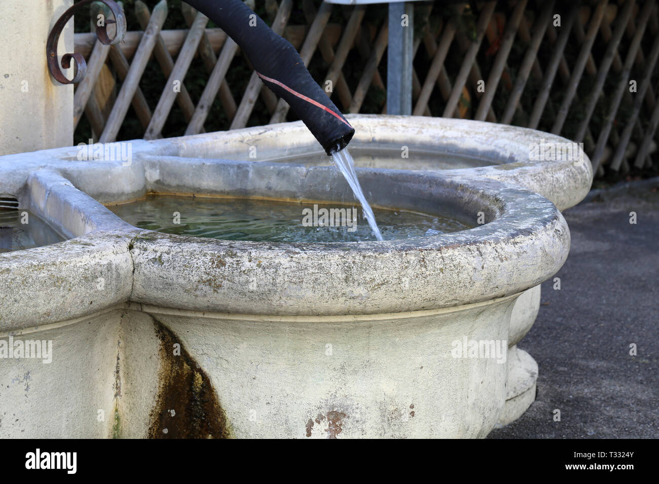 Details einer Trinkbrunnen in Nyon, Schweiz. Dieser Brunnen ist mit hellem  beige Beton hergestellt und hat die alten schwarzen Rohr wie eine  Registerkarte Stockfotografie - Alamy