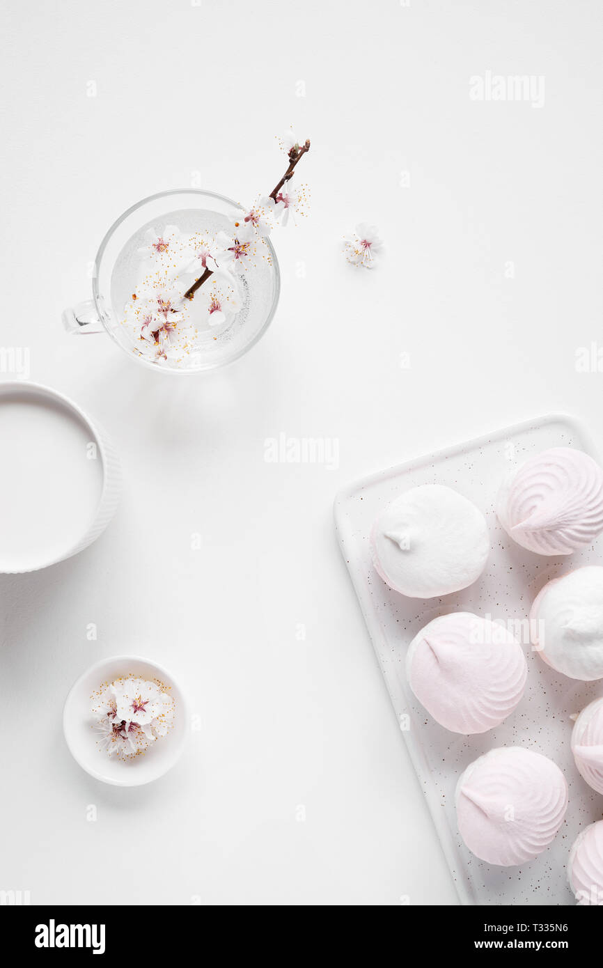 Süße hausgemachte Zephyr oder Eibisch, Milch und Blumen auf Weiß mit freier Platz für Ihren Text Stockfoto