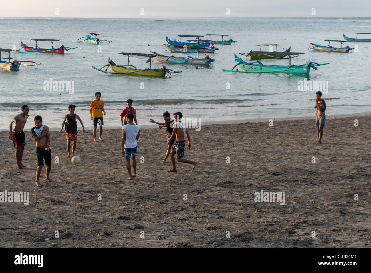 BADUNG BALI/INDONESIEN - 02 April 2019: Asiatische Jugendliche spielen Fußball oder Fußball bei Kuta Strand mit Sonnenuntergang oder goldenen Stunden Hintergrund. Der Himmel ist bewölkt und Stockfoto