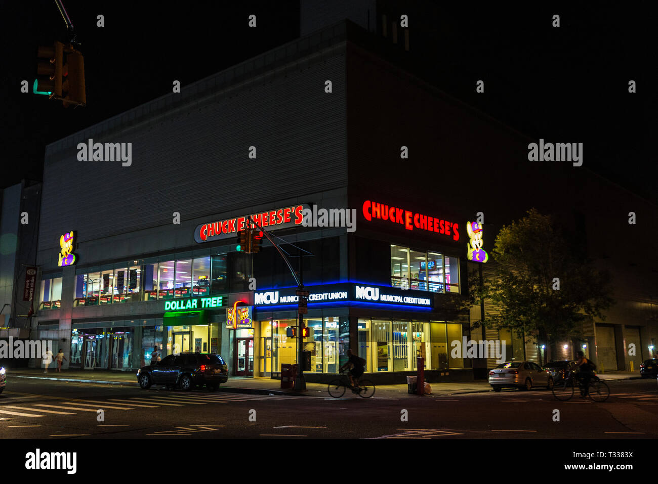 New York City, USA - 30. Juli 2018: Straße bei Nacht mit Geschäften, Bank, Radfahrer und Menschen in Harlem, Manhattan, New York City, USA Stockfoto