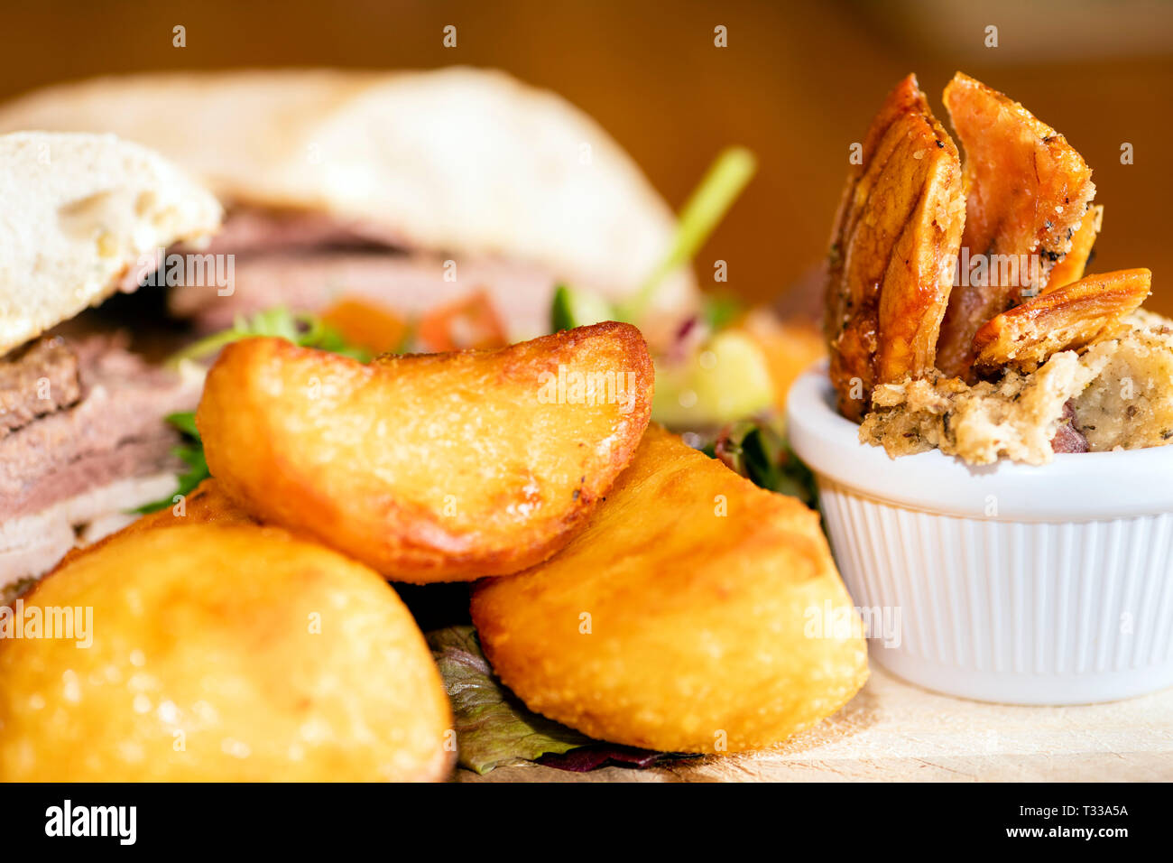 Pub essen mit Bratkartoffeln, Schweinefleisch Knistern, Füllung und ein Ciabatta Fleisch Sandwich, Großbritannien. Stockfoto