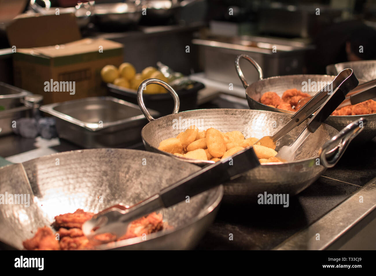 Buffet Restaurant mit drei Pfannen von Freund Essen einschliesslich Chicken Wings, Chicken Nuggets auf Anzeige unter einem Zähler Licht Stockfoto