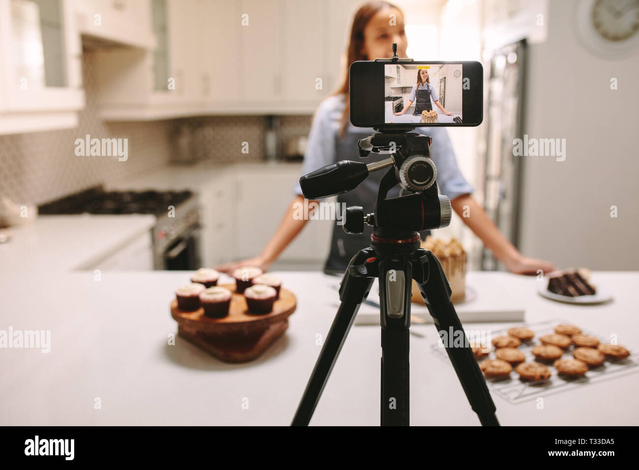 Junge weibliche Blogger das Aufzeichnen von Videos auf Handy Kamera in der Küche. Weibliche blogger video tutorial Sitzung des Backens Lektion zu Hause kitch Stockfoto