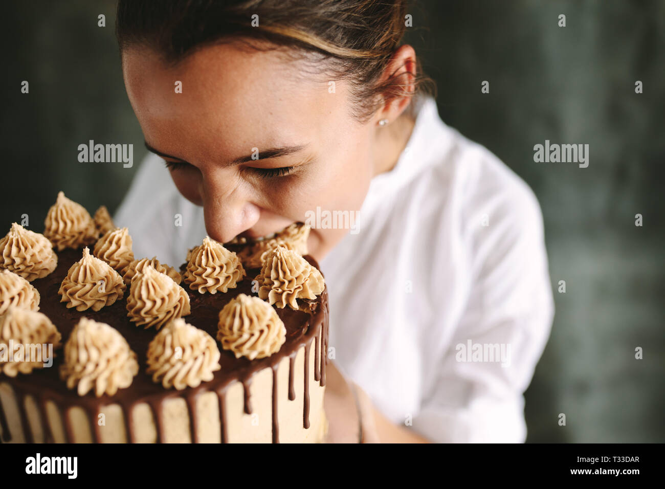 Weibliche Konditor einen großen Bissen von einem Kuchen. Konditor Essen der ganzen Kuchen. Stockfoto