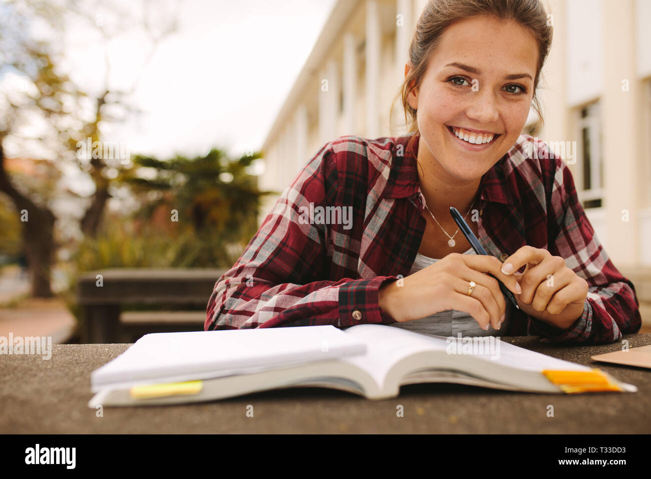 Lächelnd weibliche Student am College Campus mit Büchern sitzen. Mädchen Studenten studieren an der Universität. Stockfoto