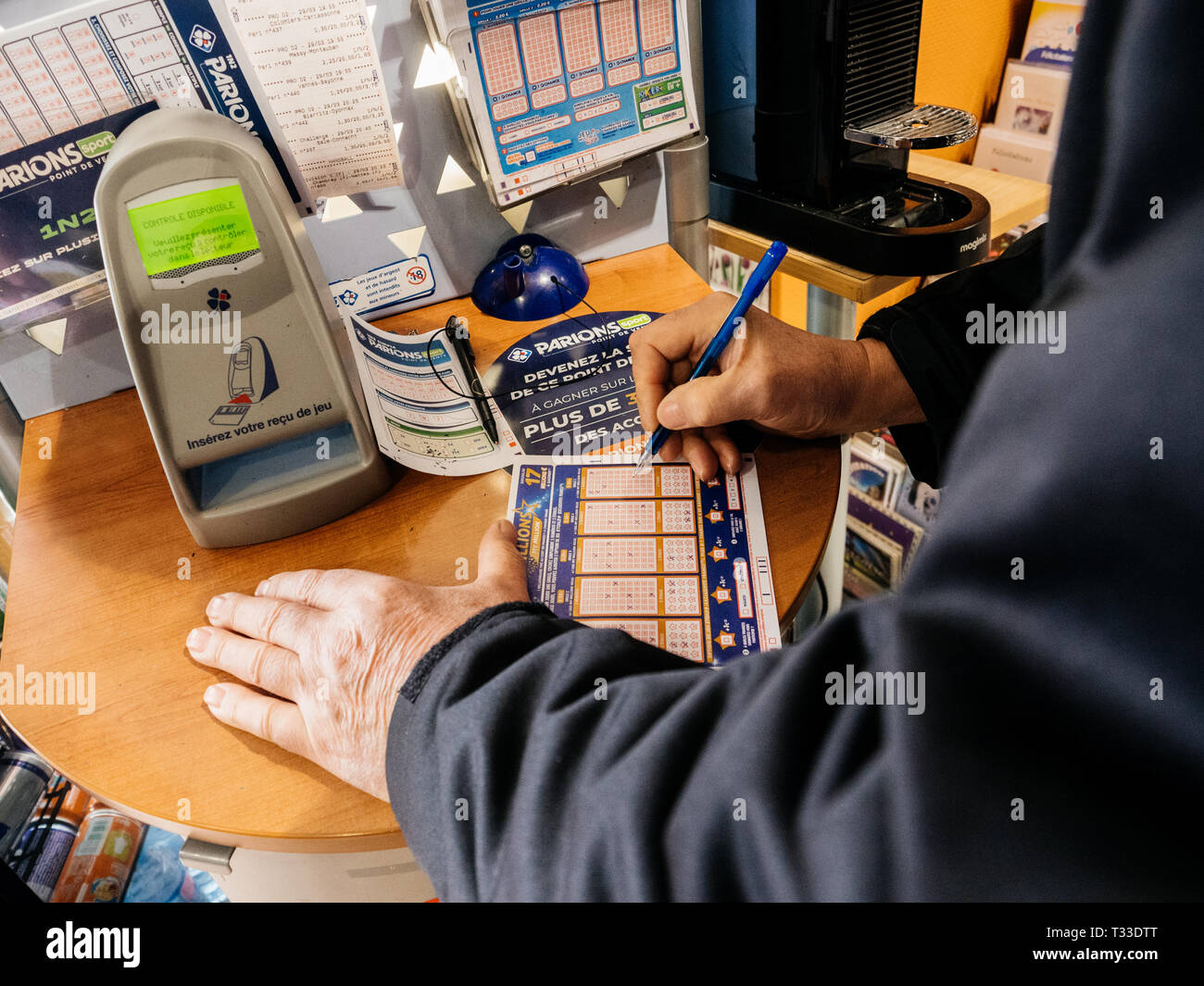 Paris, Frankreich - 29 Mar 2019: älterer Mann Kennzeichnung Zahlen auf Euromillions ticket in tabac Presse Kiosk in der Hoffnung, den großen Jackpot von 10000000 Millionen Euro zu gewinnen. Stockfoto