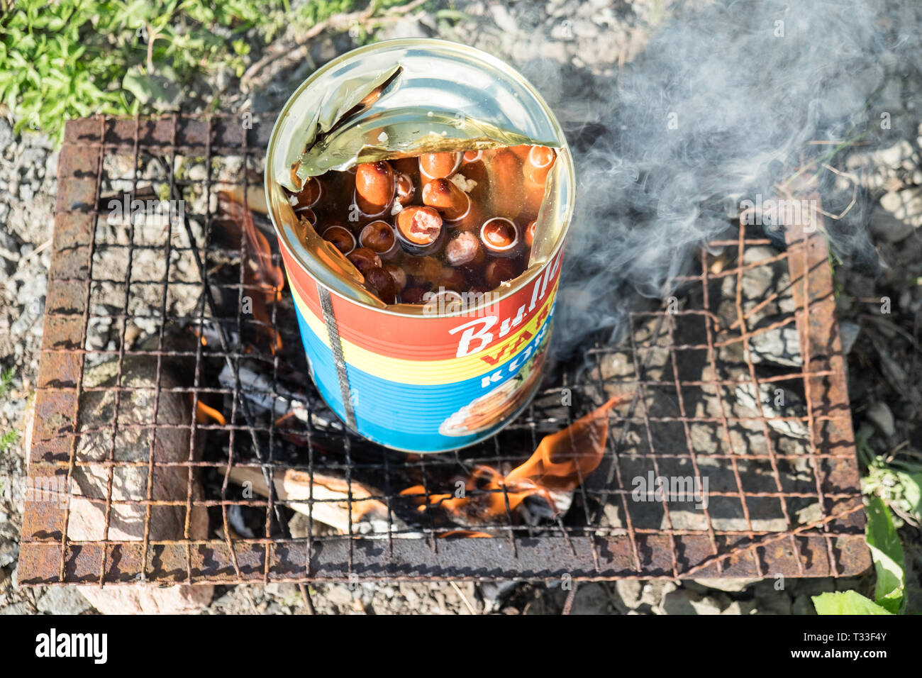 Kochen eine Dose Bullens Würstchen auf dem Grill im Freien in Schweden im Sommer. Stockfoto