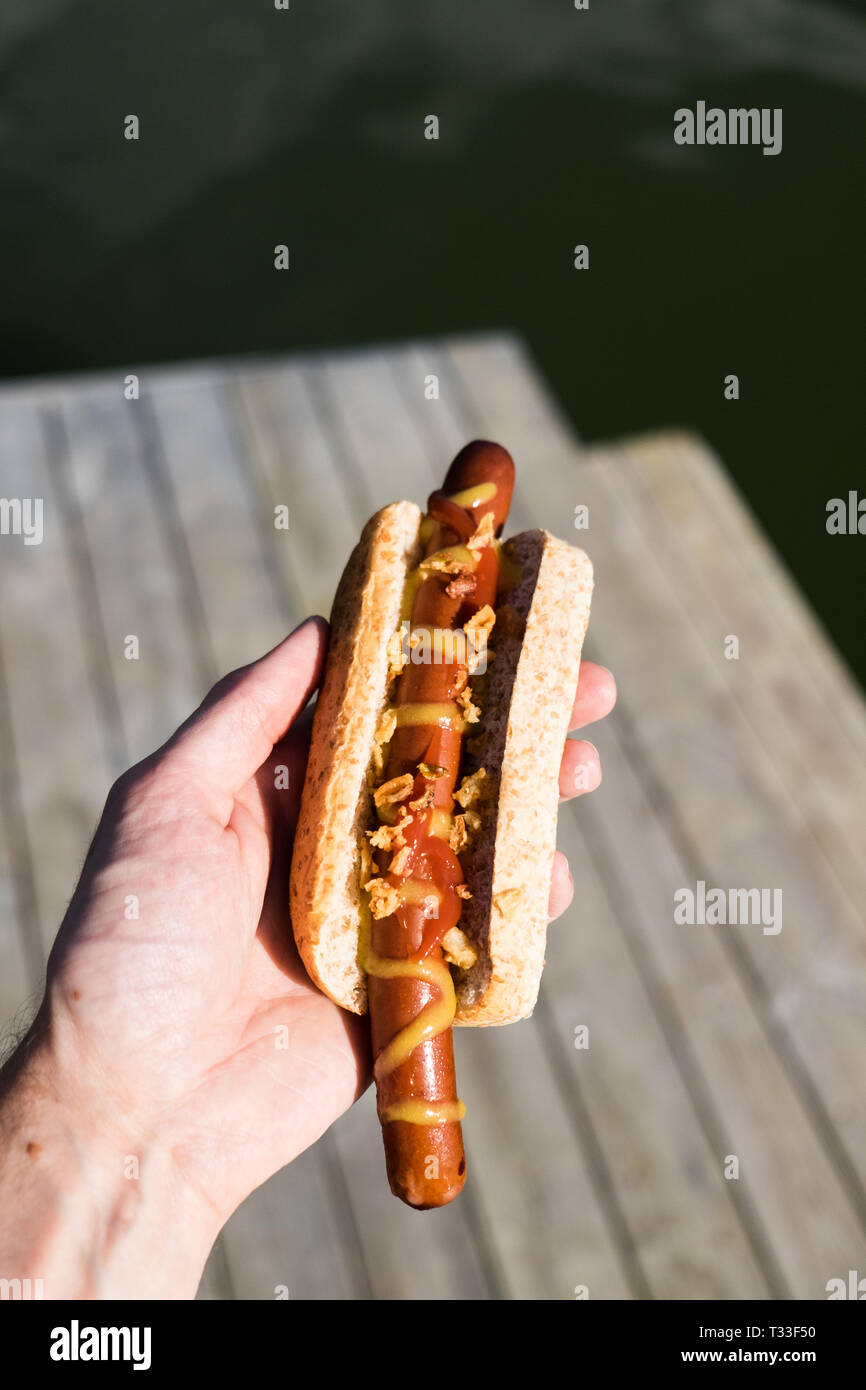 Ein bullens Hot Dog mit Senf und knusprig gebratenen Zwiebeln im Freien im Sommer in Schweden gegessen. Stockfoto