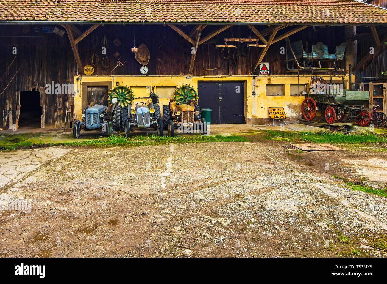 Alte landwirtschaftliche Traktoren im Hinterhof der Bauern Haus, Elsass, Frankreich. Stockfoto
