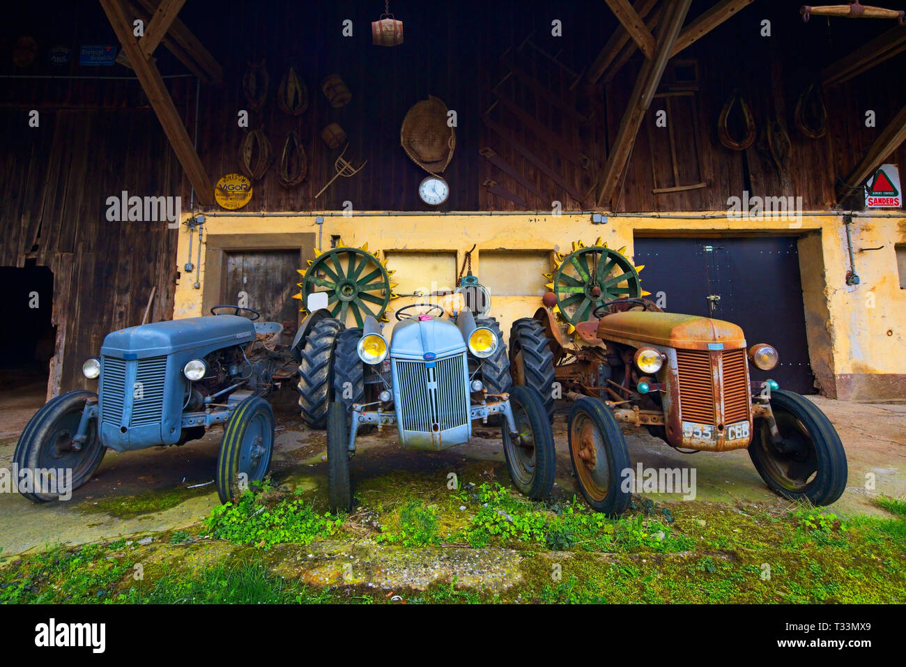 Alte landwirtschaftliche Traktoren im Hinterhof der Bauern Haus, Elsass, Frankreich. Stockfoto