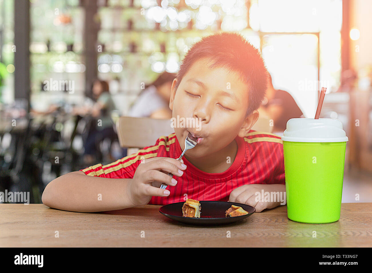 Happy Face Asian Boy genießen Sie Schokolade essen Waffel im Restaurant. Stockfoto