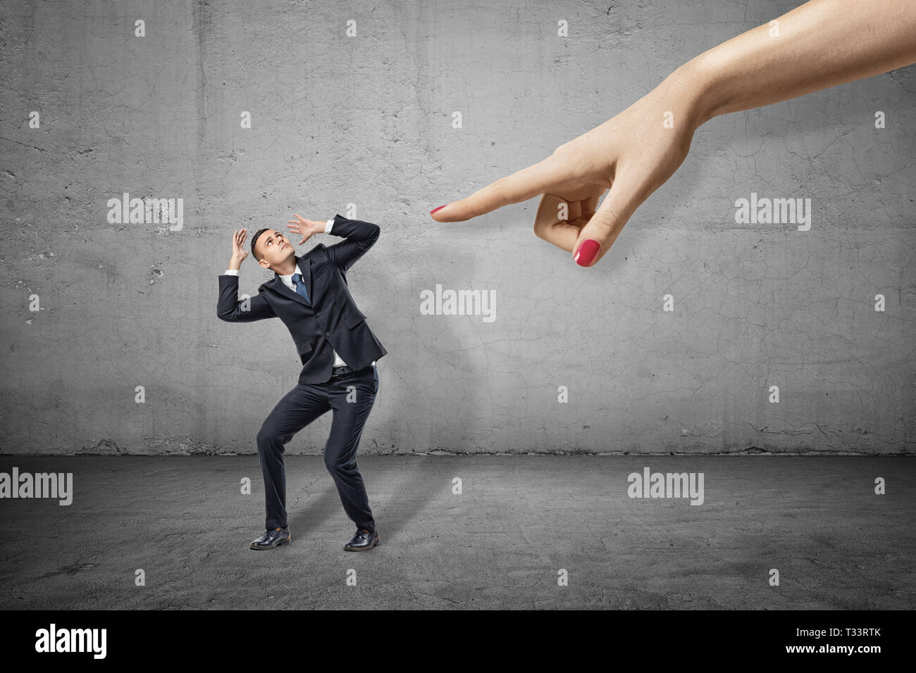 Kleine Unternehmer lehnen nach links und über seinen Kopf mit den Händen versuchte, sich aus der Hand des großen Frau auf der rechten Seite zu schützen. Stockfoto