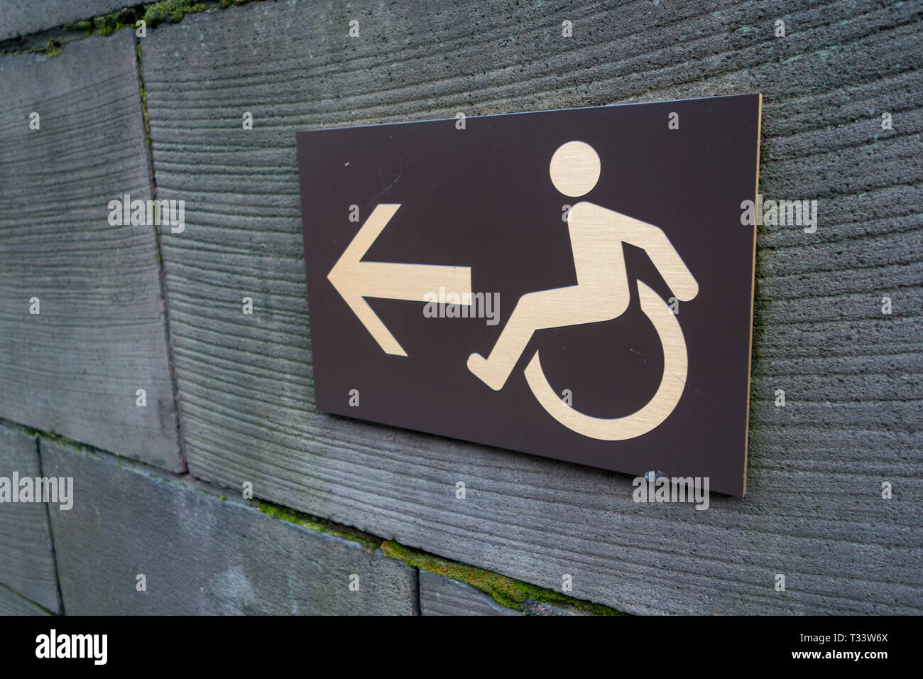 Pfeil und Rollstuhl Symbol Zeichen an der Wand in einem anagle anzeigen Stockfoto