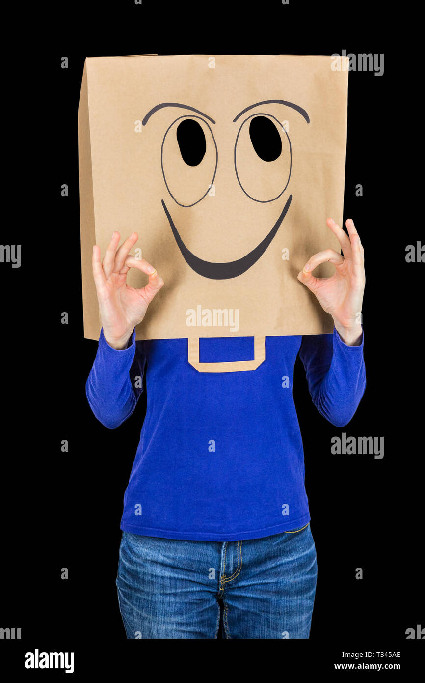 Glücklich lächelnde Frau mit papiertüte auf dem Kopf auf schwarzem Hintergrund Stockfoto