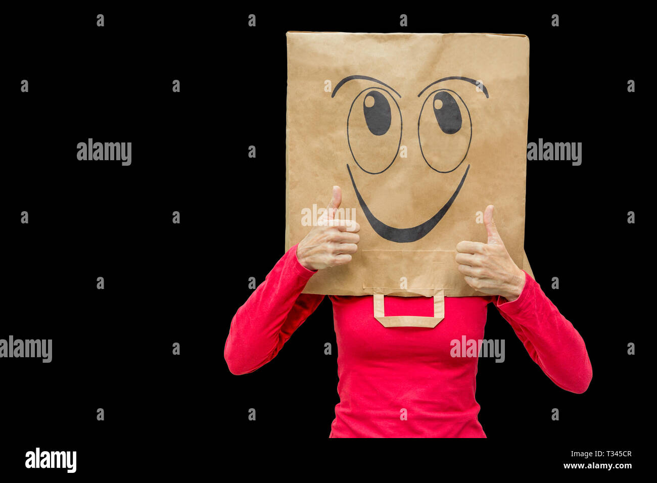 Frau mit Papiertüte mit Happy Face auf Schwarz isoliert. Sie hält ihre Daumen nach oben Stockfoto