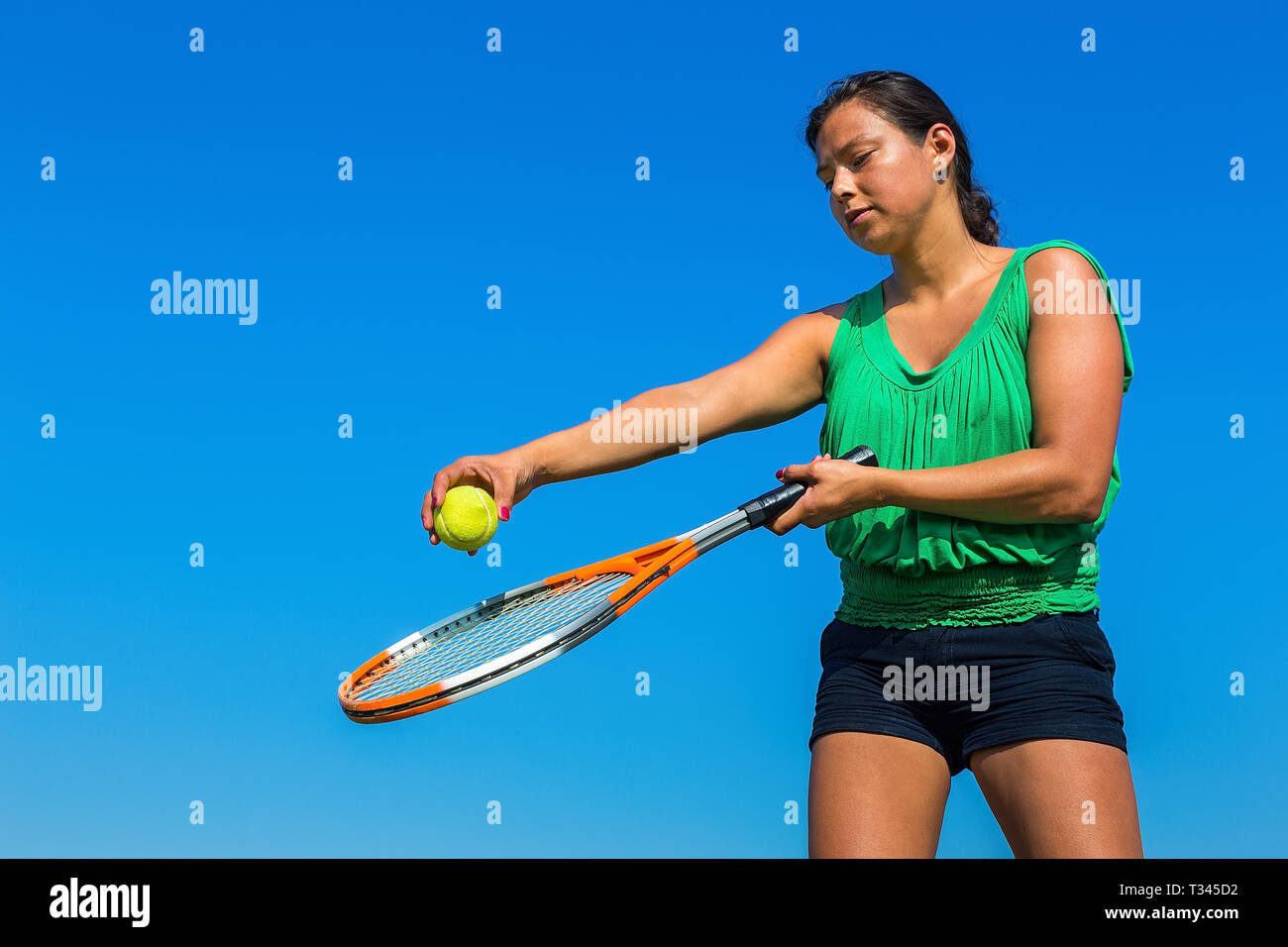 Junge kolumbianische Frau mit Tennisschläger und Ball gegen den blauen Himmel Stockfoto