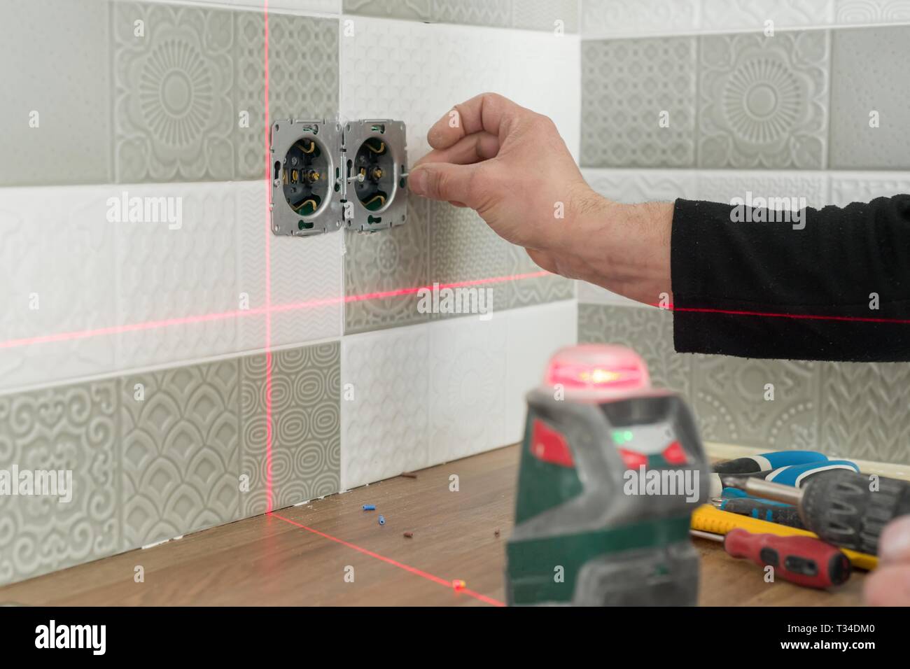 Elektriker mit Infrarot Laser level Steckdosen zu installieren. Renovierung und Bau in der Küche. Stockfoto