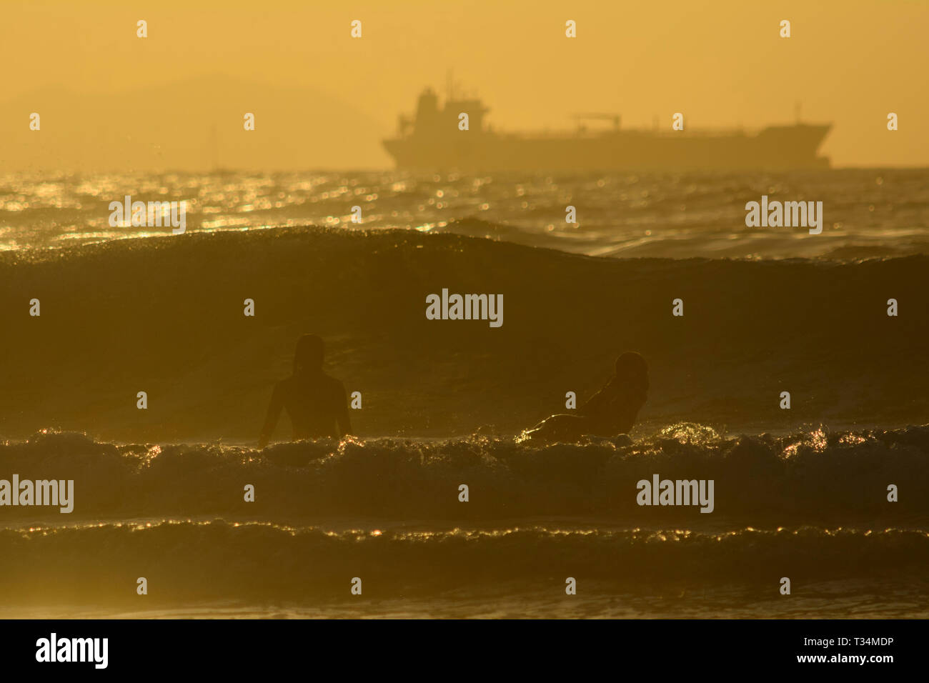 Zwei Surfer warten eine Welle bei Sonnenuntergang, Strand Sopelana, Vizcaya, Baskenland, Spanien Stockfoto