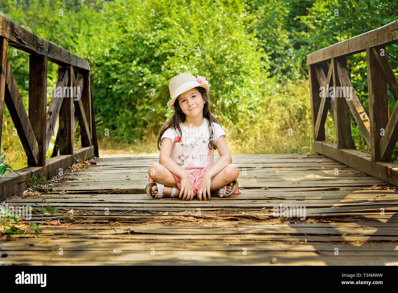Mädchen mit überkreuzten Beinen auf einer hölzernen Brücke, Bulgarien Stockfoto
