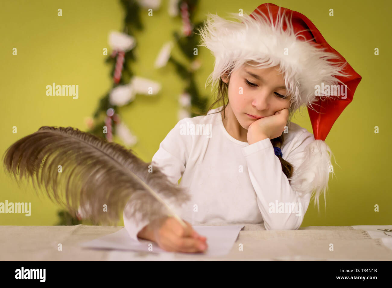 Mädchen mit einem Santa Hat einen Brief zu schreiben Santa mit Straußenfedern pen Stockfoto