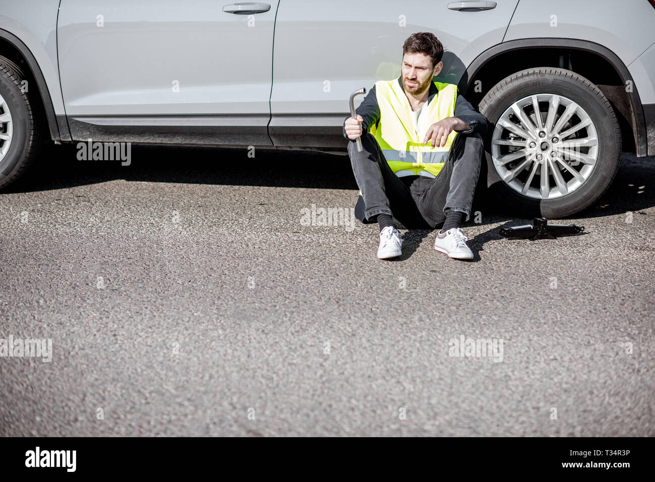 Mann mit Verzweiflung Gefühle warten auf der Straße Unterstützung in der Nähe des Auto sitzen am Straßenrand Stockfoto