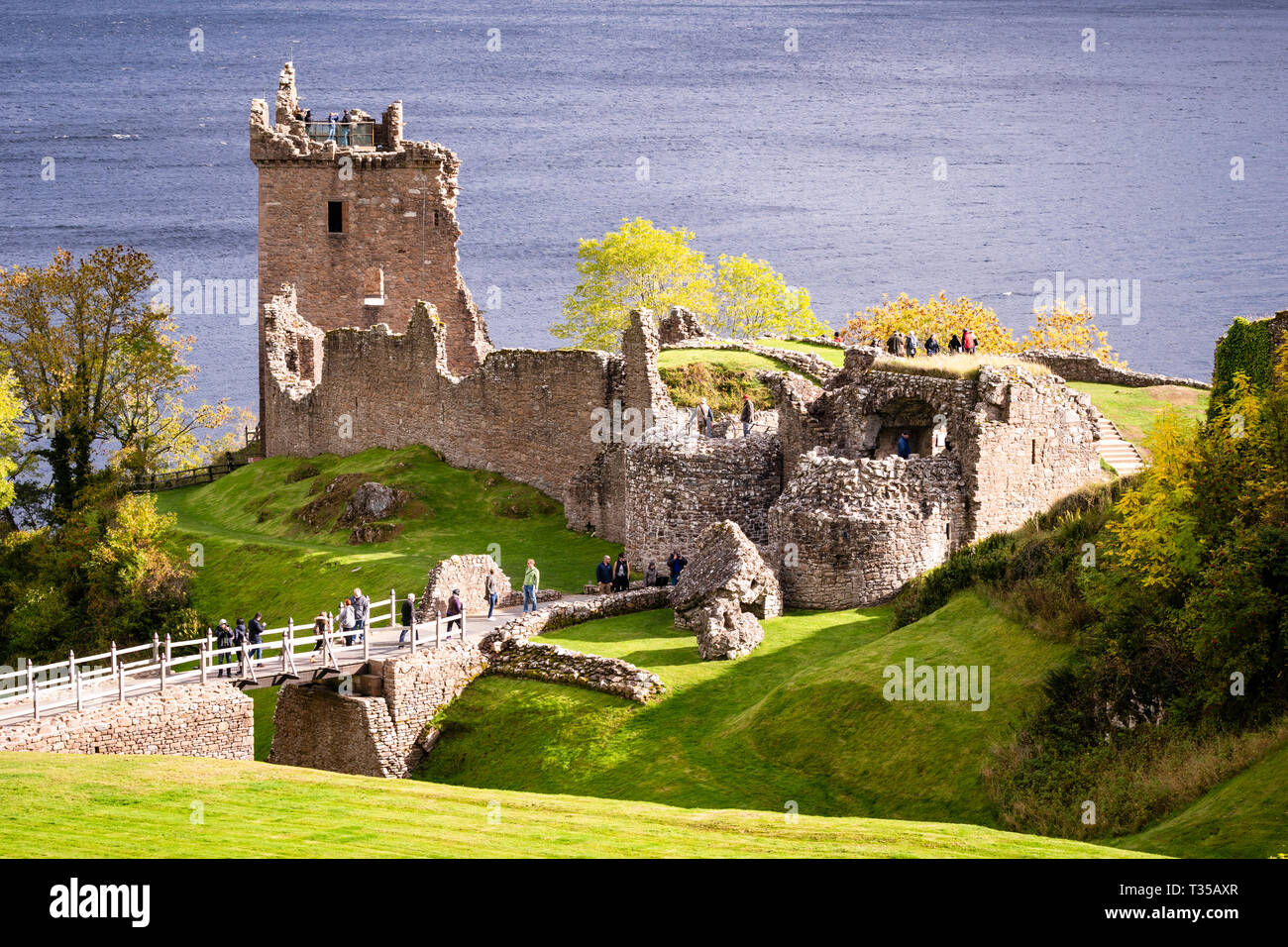 Touristen, die in der Ruine von Urquhart Castle am Ufer des Loch Ness in der Nähe von Inverness in Schottland, Großbritannien. Stockfoto