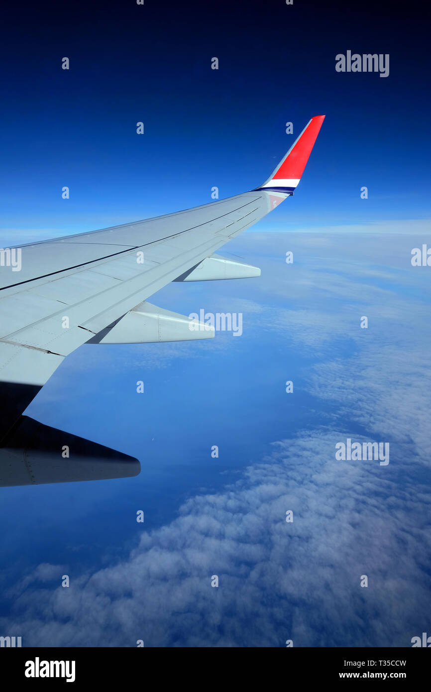 Flügel eines Flugzeugs über Dörfer oder die Landschaft fliegen. Der ebene Tragfläche auf den blauen Himmel und Erde Hintergrund Stockfoto