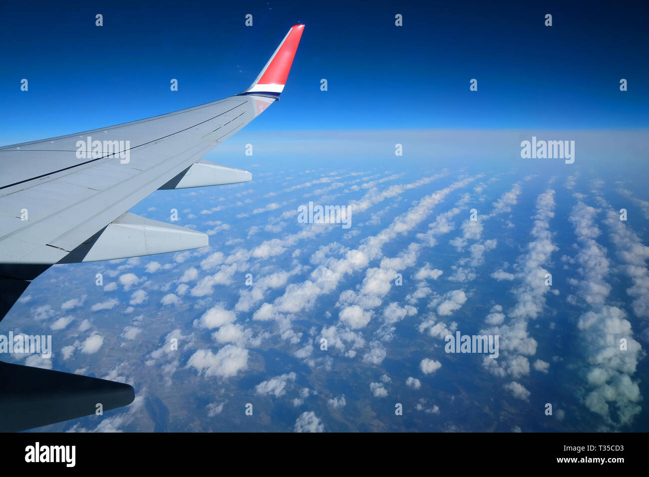 Flügel eines Flugzeugs über Dörfer oder die Landschaft fliegen. Der ebene Tragfläche auf den blauen Himmel und Erde Hintergrund Stockfoto