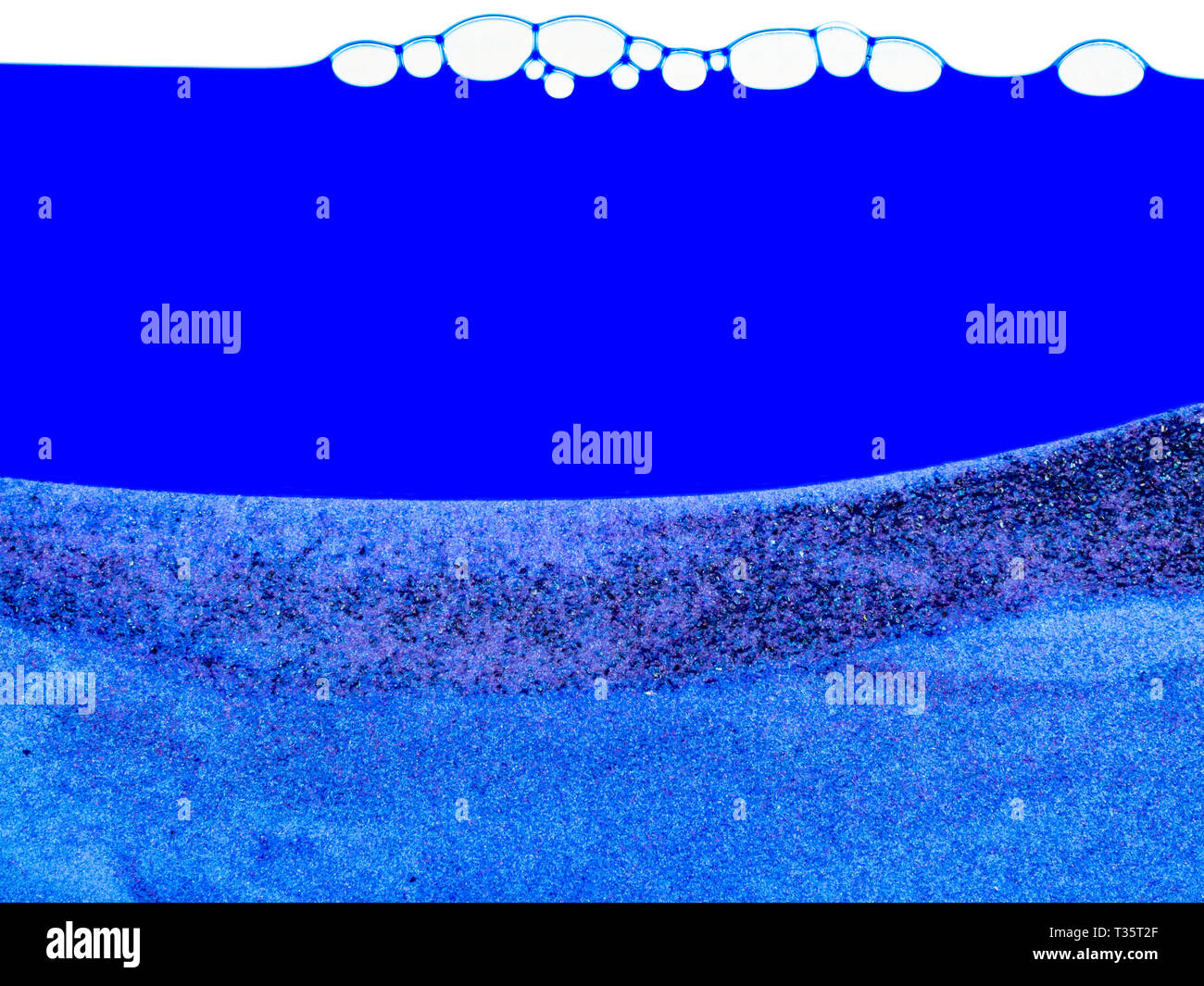 Blauer Hintergrund mit Blasen an der Spitze und einer Schicht Sand an der Unterseite. Sauberen blauen Hintergrund mit viel Platz kopieren. Stockfoto