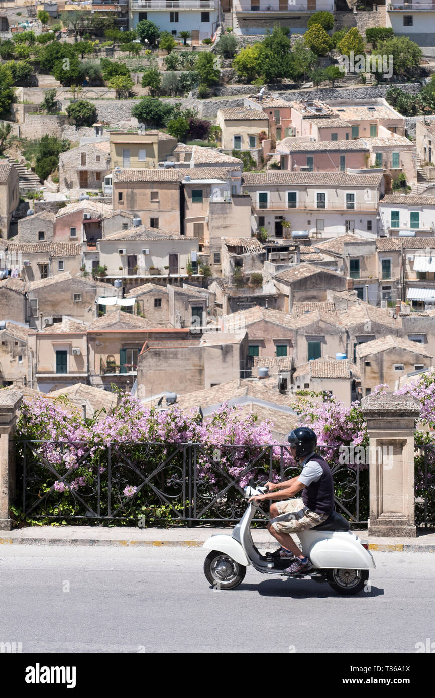 Mann, motorscooter in Hill City von Modica Alta in Richtung Modica Bassa, Sizilien, Italien suchen Stockfoto