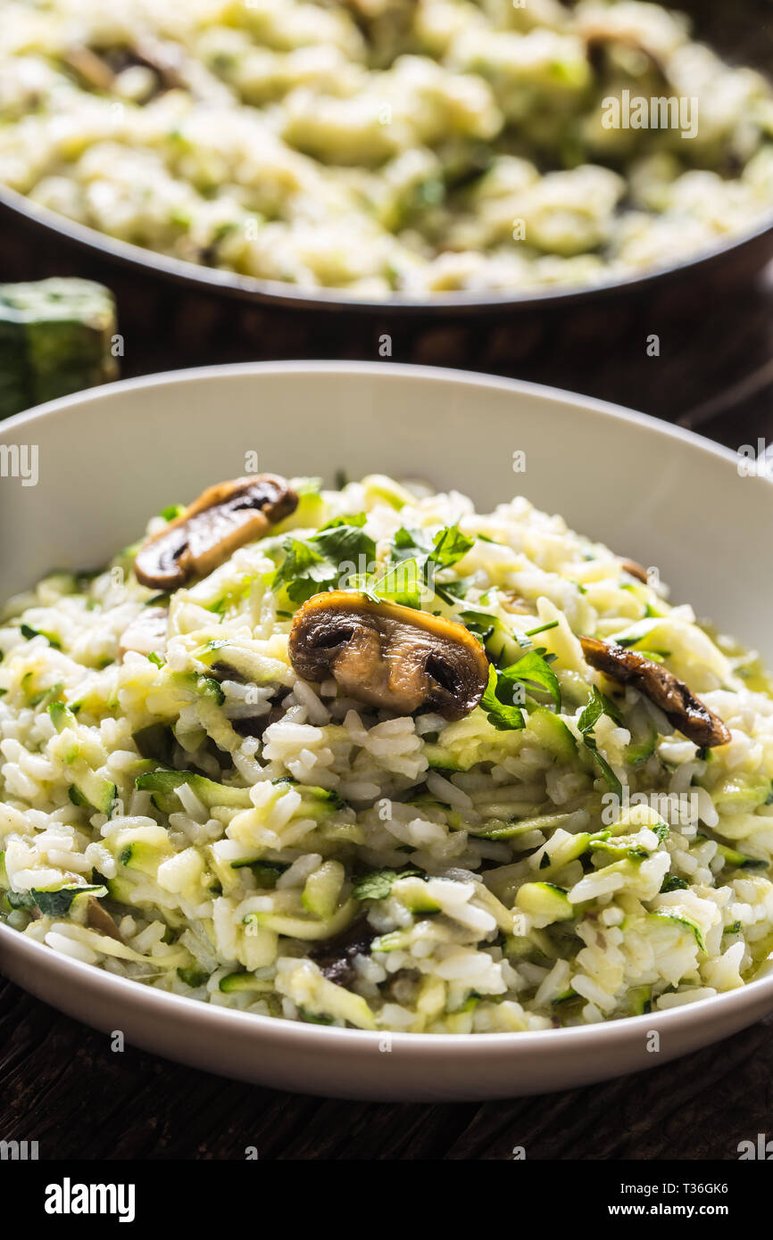 Italienische Risotto mit Zucchini Champignons und Parmesan in weiße Platte. Stockfoto