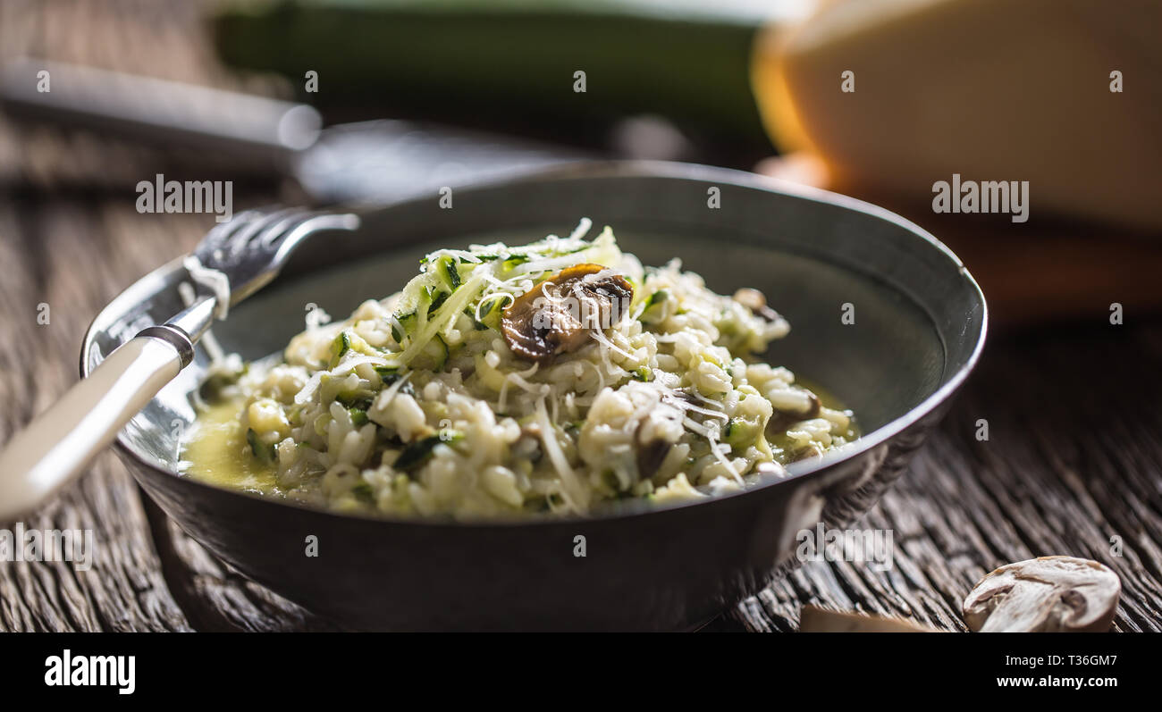 Italienische Risotto mit Zucchini Champignons und Parmesan in dunklen Platte. Stockfoto