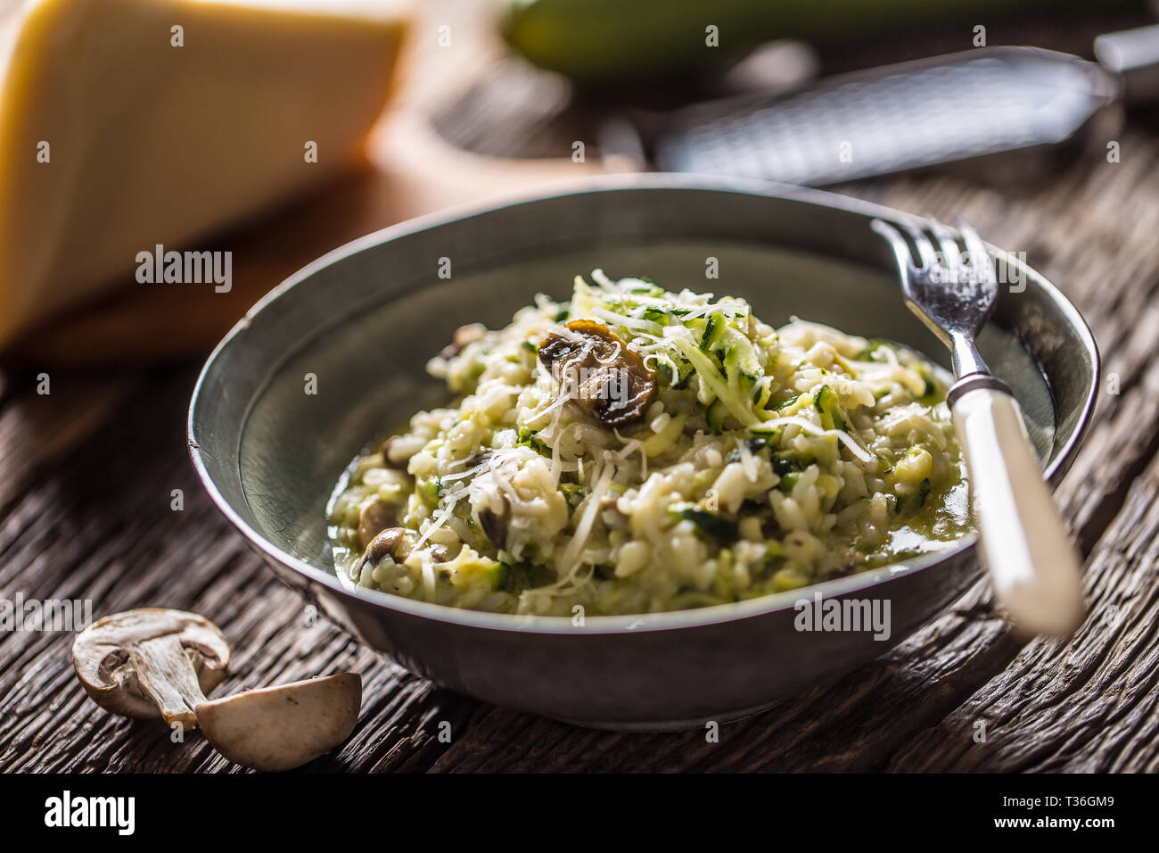 Italienische Risotto mit Zucchini Champignons und Parmesan in dunklen Platte. Stockfoto