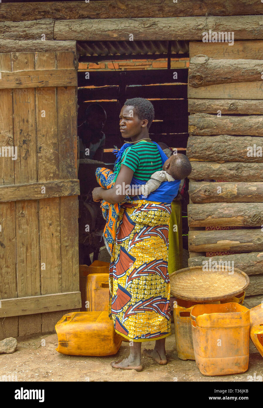 Malawische Frau mit Baby auf dem Rücken und warten an Mais Mühle im Dorf Chiphazi Stockfoto