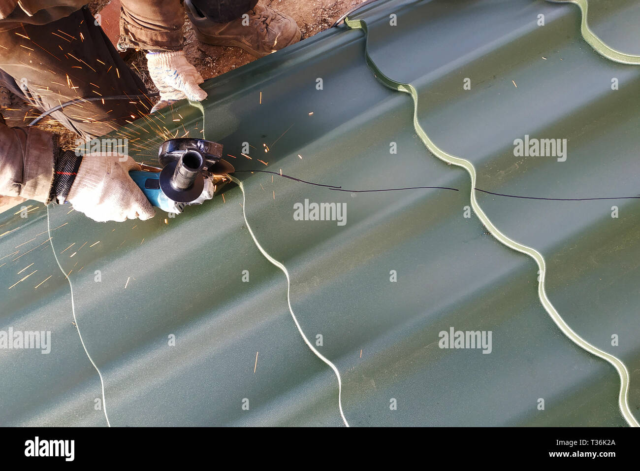 Der Master schneidet eine professionelle Blech für die Installation auf dem Dach des Hauses 2019 Stockfoto
