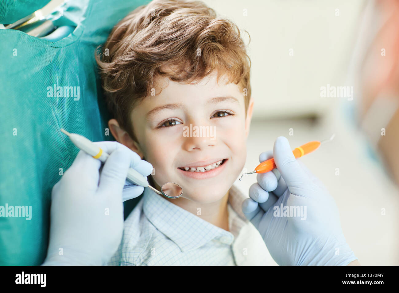 Kind lächelnd, während im Zahnarztstuhl sitzen. Stockfoto