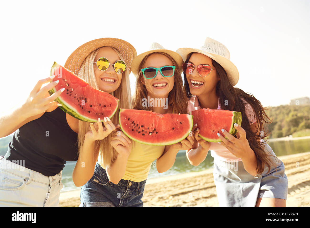 Lachende Frauen mit Wassermelone am Strand Stockfoto
