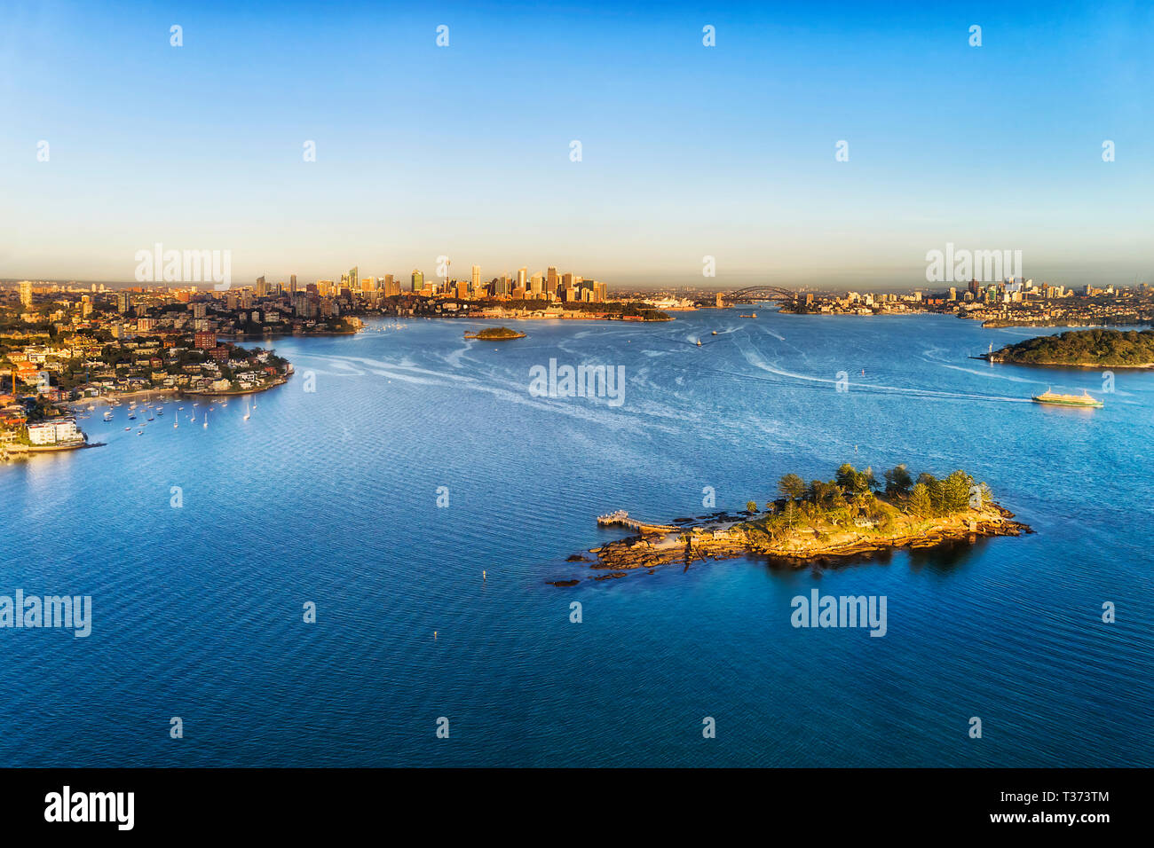 Blaue Wasserfläche von Sydney Harbour von Shark Island in Double Bay in Richtung entfernten Stadt CBD und die Harbour Bridge zwischen Ufer von Sydney. Stockfoto