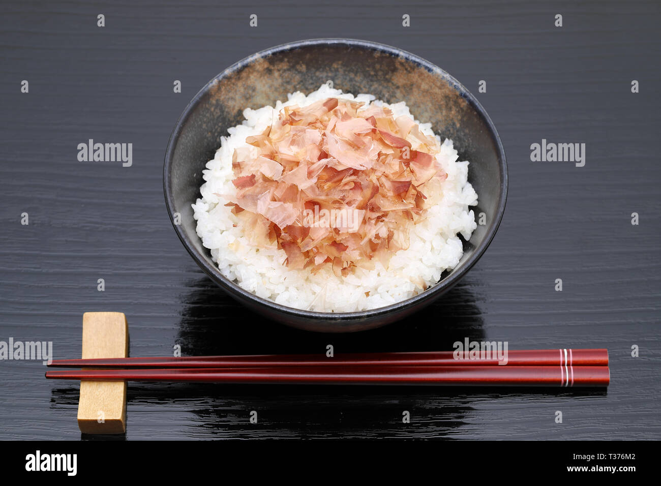 Japanisches Essen, Katuobushi auf gekochten Reis weiß auf schwarzem Hintergrund Stockfoto